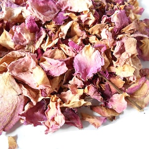 May include: Close-up of dried rose petals in pink, purple, and tan hues. The petals are scattered on a white surface, creating a textured, natural look. Suitable for potpourri, crafts, or decorative use.