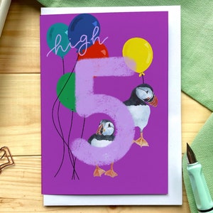 May include: A purple birthday card with a large number 5 in the center. The number is surrounded by colorful balloons and two puffins. The text "high 5" is written above the number.
