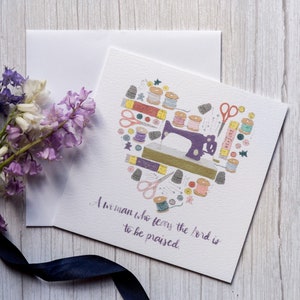 May include: A white card with a purple heart-shaped design featuring a sewing machine and various sewing supplies. The text "A man who fears the Lord is to be praised" is written in black cursive.