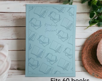 Può includere: Un diario di lettura azzurro con un motivo ripetuto di libri aperti e foglie. Le parole "Reading Journal" sono al centro. Il diario rettangolare ha il testo "Fits 60 books" in basso.