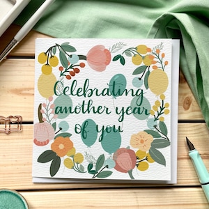 Verjaardagskaart: weer een jaar: moderne kalligrafie, bloemen en ballonnen in groenblauw en mosterdgeel