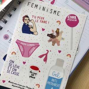 May include: A sheet of stickers with a feminist theme. The stickers feature illustrations of a woman flexing, a lollipop with "Girl Power" text, and text in French. Other stickers include a pair of underwear and a bottle of gel.