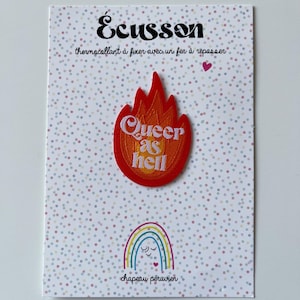 May include: A decorative patch with a flame design in red and orange, featuring the text "Queer as Hell." The patch is on a card with a dotted background and the text "Écusson" and "chapeau péruvien."
