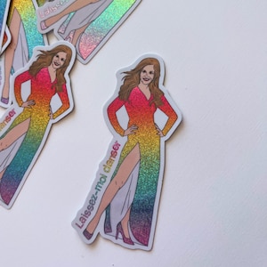 May include: Stickers featuring a woman in a long, rainbow-colored dress with a high slit. The stickers have a holographic, glittery finish and the text "Laissez-moi danser" is printed on them.