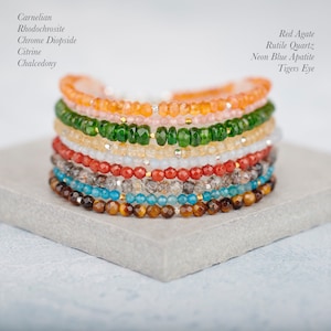 Puede incluir: Una pila de ocho pulseras de piedras preciosas facetadas que incluyen cornalina, rodocrosita, di&oacute;psido de cromo, citrino, calcedonia, &aacute;gata roja, cuarzo rutilado, apatita azul ne&oacute;n y ojo de tigre, con peque&ntilde;as cuentas met&aacute;licas entre ellas.