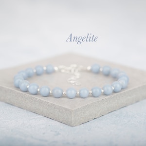 May include: A beaded bracelet featuring smooth, light blue Angelite gemstone spheres alternating with small, polished silver-tone metal spacer beads. The bracelet includes a silver-tone metal chain extender and is labeled with the text Angelite.
