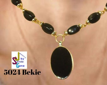 May include: A black beaded necklace with a gold-colored chain and a black oval pendant. The necklace is displayed on a person. The image also includes the text "5024 Bekie".