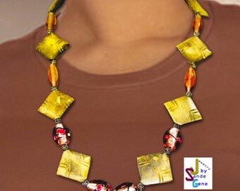 May include: A necklace featuring alternating yellow diamond-shaped flat beads and smaller amber-colored oval beads, interspersed with dark, speckled round beads. The design includes small silver-toned spacers. Text reads: Jewelry by Sande Gene 5020 Vairy.