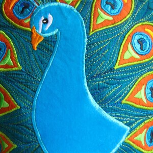 May include: A blue peacock pillow with a teal background and colorful embroidered feathers. The peacock's head and neck are also embroidered.
