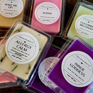May include: Assortment of soy wax melts in clear plastic packaging. Scents include "Wake Me Up!", "Aloha", "Cucumber Melonade", "Allergy Calm", and "Inner Goddess". Each melt is a different color, with labels indicating scent and ingredients.