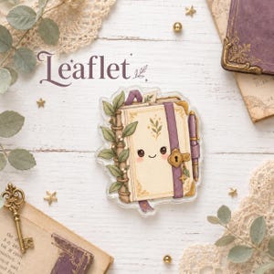 Könnte beinhalten: Ein gestanzter Aufkleber, der ein cremefarbenes Buch mit einem lächelnden Gesicht, einem violetten Riemen, einem goldenen Schloss und einem seitlich befestigten Stift zeigt. Das Buch ist mit grünen Blättern und Ranken verziert. Das Wort Leaflet steht darüber.