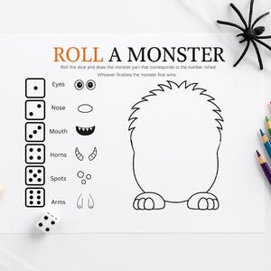 May include: A white sheet of paper with the text "ROLL A MONSTER" and a monster outline. The game includes dice, monster parts, and colored pencils. A black spider and candy corn are also present.