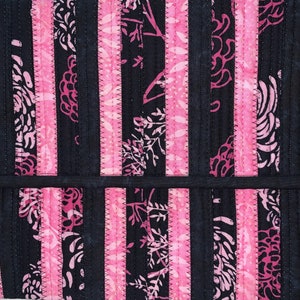 May include: A black and pink striped fabric with a floral pattern. The fabric is quilted and has a subtle sheen.