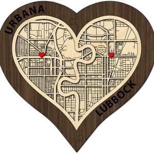 May include: A wooden heart-shaped map puzzle with two red hearts marking the locations of Urbana and Lubbock. The puzzle is made of two pieces that fit together to form a complete heart.