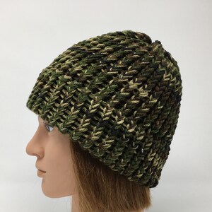 May include: A green, brown, and black camouflage knit beanie hat.