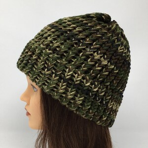 May include: A green, brown, and black camouflage knit beanie hat.