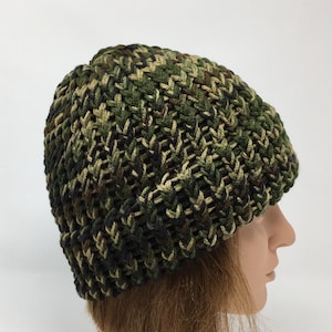 May include: A green, brown, and black camouflage knit beanie hat.