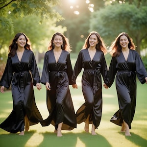 May include: Four women wearing black satin robes with a sash tie at the waist. The women are walking in a line, smiling at the camera.