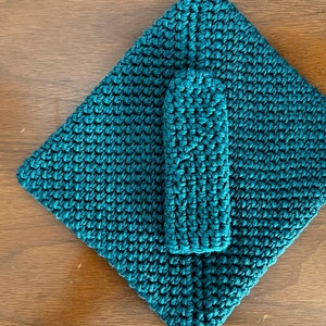 May include: A teal blue crocheted blanket and a matching teal blue crocheted potholder.