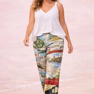 May include: A white sleeveless V-neck camisole top paired with loose-fitting trousers featuring a colourful vintage-style map print. The trousers display various illustrations of landscapes, buildings, and text including "Lake District" and "A Road to".