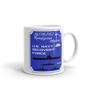Puede incluir: Taza de cerámica blanca con un gráfico azul y blanco de un barco de la Fuerza de Recuperación de la Marina de los EE. UU. con el texto "GEMINI Rendezvous Mission GTA-11 Pacific".