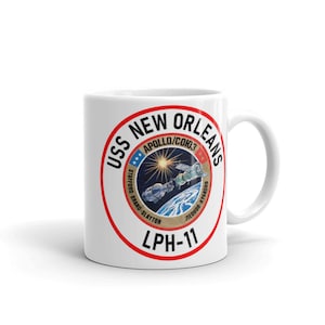 May include: White ceramic mug with a red circle graphic featuring the text "USS NEW ORLEANS LPH-11" and a depiction of the Apollo-Soyuz Test Project, a joint US-Soviet space mission.