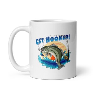 May include: White ceramic coffee mug with a blue and green illustration of a fish jumping out of the water with a fishing rod and the text "GET HOOKED!"