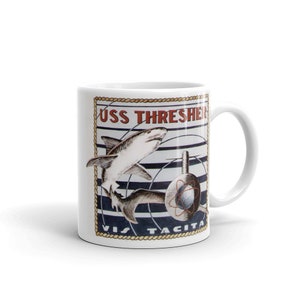 May include: White ceramic mug with a graphic of a shark and a submarine. The graphic is surrounded by a rope border and the text "USS THRESHER VIS TACITA".