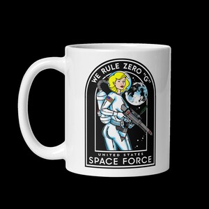 May include: White ceramic mug with a black and white illustration of a woman in a space suit holding a gun. The text "We Rule Zero 'G' United States Space Force" is printed on the mug.