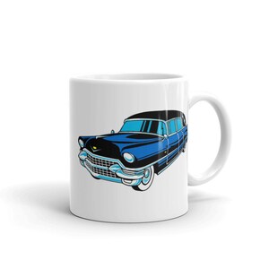 May include: White ceramic mug with a blue and black vintage car illustration. The car has a black roof and a chrome bumper.
