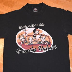 Puede incluir: Camiseta negra con una ilustración de dibujos animados de una familia en un coche. El texto "There's No Value Like Family Values" está impreso en la camiseta.