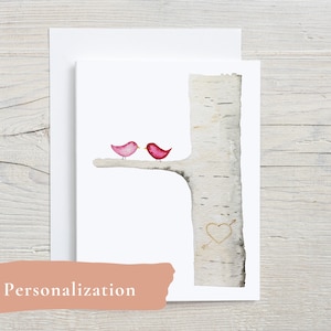 May include: A watercolor illustration of two pink birds perched on a branch of a birch tree. The tree trunk has a heart with an arrow carved into it.