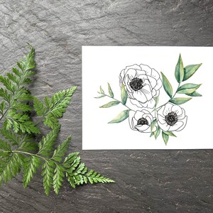 Pu&ograve; includere: Un biglietto bianco con un disegno in bianco e nero di tre fiori e foglie verdi. I fiori sono stilizzati e assomigliano ad anemoni. Il biglietto &egrave; su uno sfondo grigio scuro.