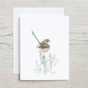 May include: A watercolor painting of a small, gray bird perched on a branch of green leaves. The bird has a long, thin tail and a small, pointed beak.