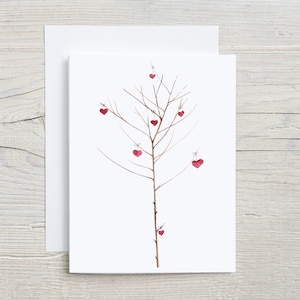 May include: A white card with a watercolor illustration of a bare tree with red hearts hanging from the branches.