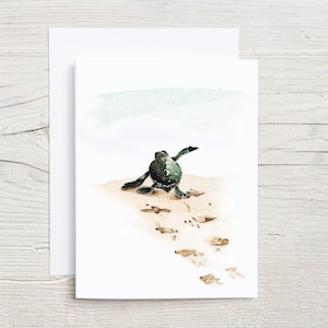 May include: Watercolor painting of a baby sea turtle walking on a sandy beach, leaving footprints behind it. The turtle is facing away from the viewer, with its flippers outstretched.