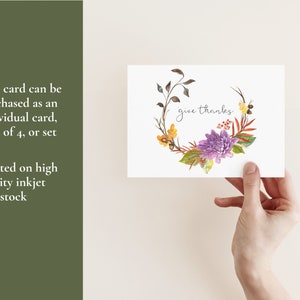 May include: A watercolor thank you card with a floral wreath in shades of purple, yellow, and orange. The text "give thanks" is written in the center of the wreath.