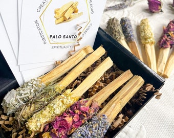 May include: A set of six Palo Santo sticks bundled with dried flowers and herbs. The sticks are in a black box with brown shredded paper. The box is surrounded by cards with the words "Palo Santo", "Meditation", "Healing", "Creativity", "Purification", "Connection", and "Spirituality".