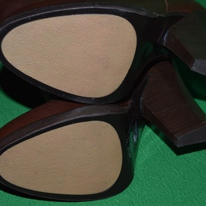 May include: Close-up of the bottom of two brown leather boots with a beige leather insole. The boots have a high heel.