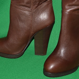 May include: A pair of brown leather knee-high boots with a chunky heel.