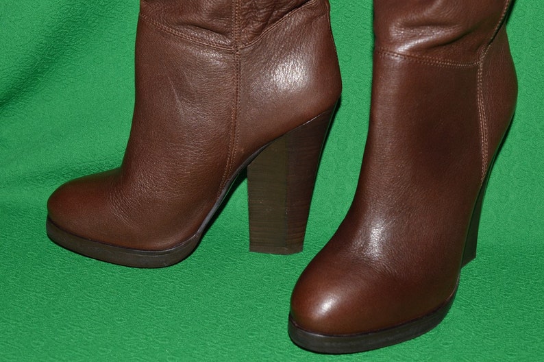 May include: A pair of brown leather knee-high boots with a chunky heel.
