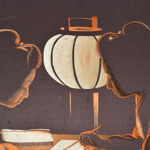 May include: Two women in traditional Japanese clothing are seated at a table under a paper lantern. One woman is writing in a book while the other looks on.