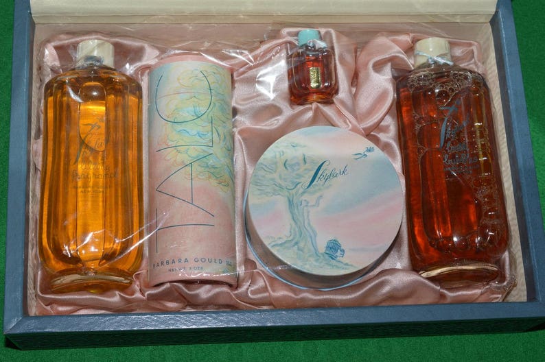 Pu&ograve; includere: Un set di flaconi di profumo vintage e una confezione compatta in una scatola rosa e bianca. I flaconi sono in vetro trasparente con dettagli dorati e la confezione compatta &egrave; rotonda con un design floreale. La scatola &egrave; rivestita in raso rosa.