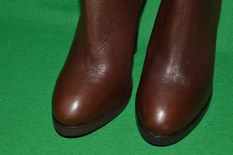 May include: A pair of brown leather ankle boots with a rounded toe and a low heel.