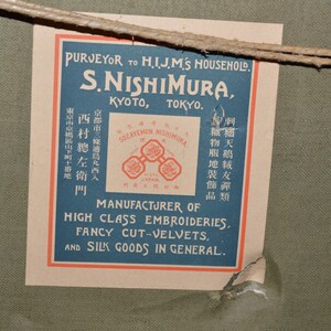 May include: A vintage label with blue and red text on a cream background. The label reads "Purveyor to H.I.J.M.'s Household. S. Nishimura, Kyoto, Tokyo. Sozayemon Nishimura, Japan. Manufacturer of High Class Embroideries, Fancy Cut-Velvets, and Silk Goods in General."