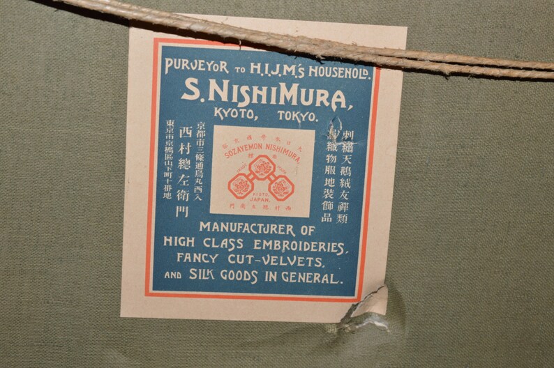 May include: A vintage label with blue and red text on a cream background. The label reads "Purveyor to H.I.J.M.'s Household. S. Nishimura, Kyoto, Tokyo. Sozayemon Nishimura, Japan. Manufacturer of High Class Embroideries, Fancy Cut-Velvets, and Silk Goods in General."