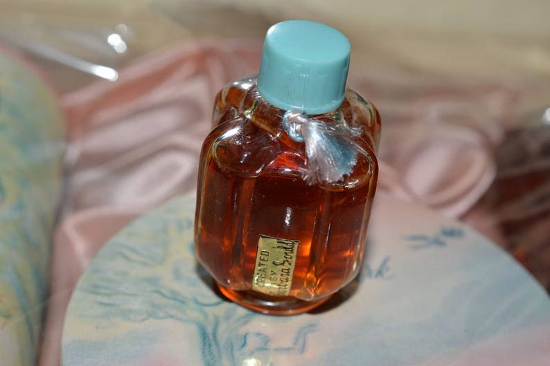 Pu&ograve; includere: Un piccolo flacone di vetro trasparente con un tappo blu chiaro e un liquido marrone all'interno. Il flacone ha un'etichetta con la scritta "Concentrated Extract of Scotch" in lettere dorate.
