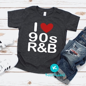 May include: A dark gray t-shirt with a white graphic that says "I love 90s R&B" with a red heart in place of the word "love".