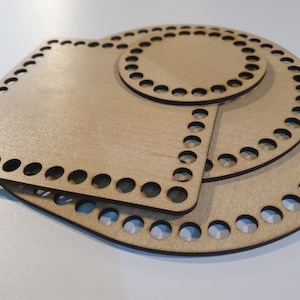 Könnte beinhalten: Drei übereinander gestapelte Holz-Häkelringe in verschiedenen Größen. Die Ringe sind aus hellem braunem Holz gefertigt und haben eine glatte Oberfläche. Die Ringe sind für Häkelprojekte konzipiert.