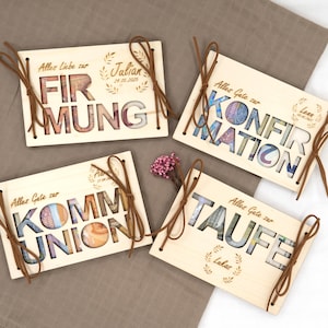 May include: Four wooden money boxes with different occasions: Confirmation, Communion, First Communion, and Baptism. Each box has a cutout design of the occasion's name with a money bill visible through the cutout. The boxes are tied with brown ribbon.
